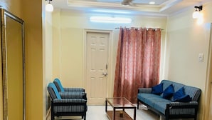 Uma sala de estar moderna com sofá, poltrona, mesa de centro e banquinho.