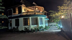A two-story building with a balcony, surrounded by plants and a gravel path. - Kilimanjaroo Inn (Moshi)