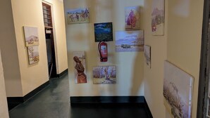A hallway with various artworks on the walls, a fire extinguisher, and a sign that reads "KARIBU". - Kilimanjaroo Inn (Moshi)