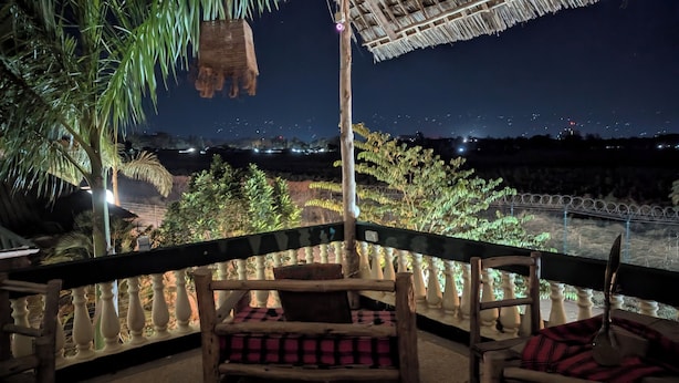 A balcony with a view of a cityscape at night, featuring a railing, chairs, and a hanging planter. - Kilimanjaroo Inn (Moshi)