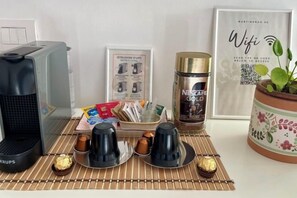 A kitchen counter with a coffee maker, a Nespresso Gold coffee pod dispenser, a framed instruction manual, a potted plant, and a Wifi sign. - Martinengo30 - Milano Metro M3 (Milan)