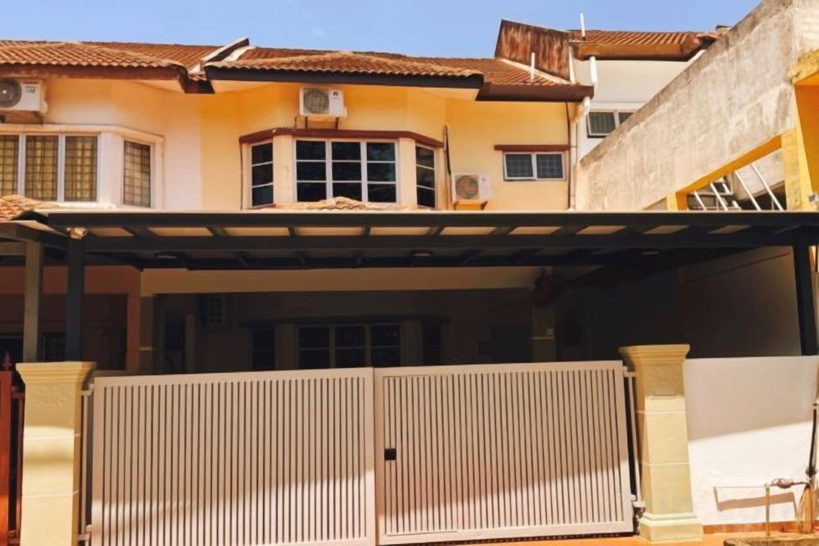 A residential building with a gated entrance, a covered porch, and a tiled roof.
