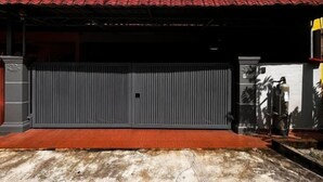 A closed garage door with a red roof and a concrete ground. - Seremban-Spacious-Lovely-Home-Bkt Chedang-S2-10R4B (Seremban)
