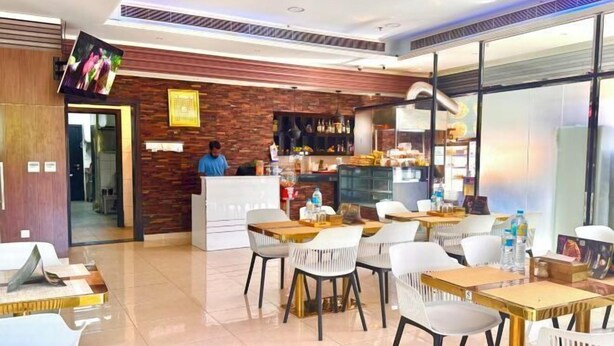 A modern restaurant with a bar area, white chairs, and a counter.