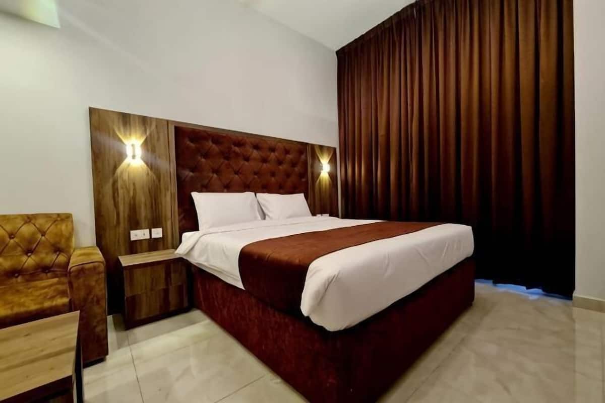 Ein Hotelzimmer mit einem großen Bett, einem Holzkopfteil, zwei Nachttischen und einem Beistelltisch.