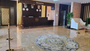 A reception area with a reception desk, a chandelier, a clock, and a patterned rug.