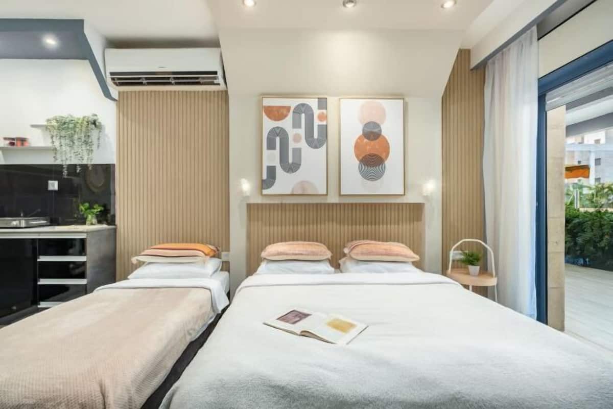 A modern hotel room with a bed, bedside tables, a desk, and a window with a view.