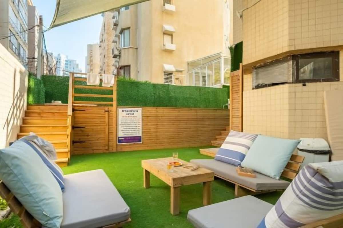 A courtyard with outdoor seating, a wooden table, and a sign.