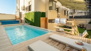 A rooftop pool area with a wooden deck, lounge chairs, and a canopy. - Netanya Beach & Pool Elegant Studio (Netanya)