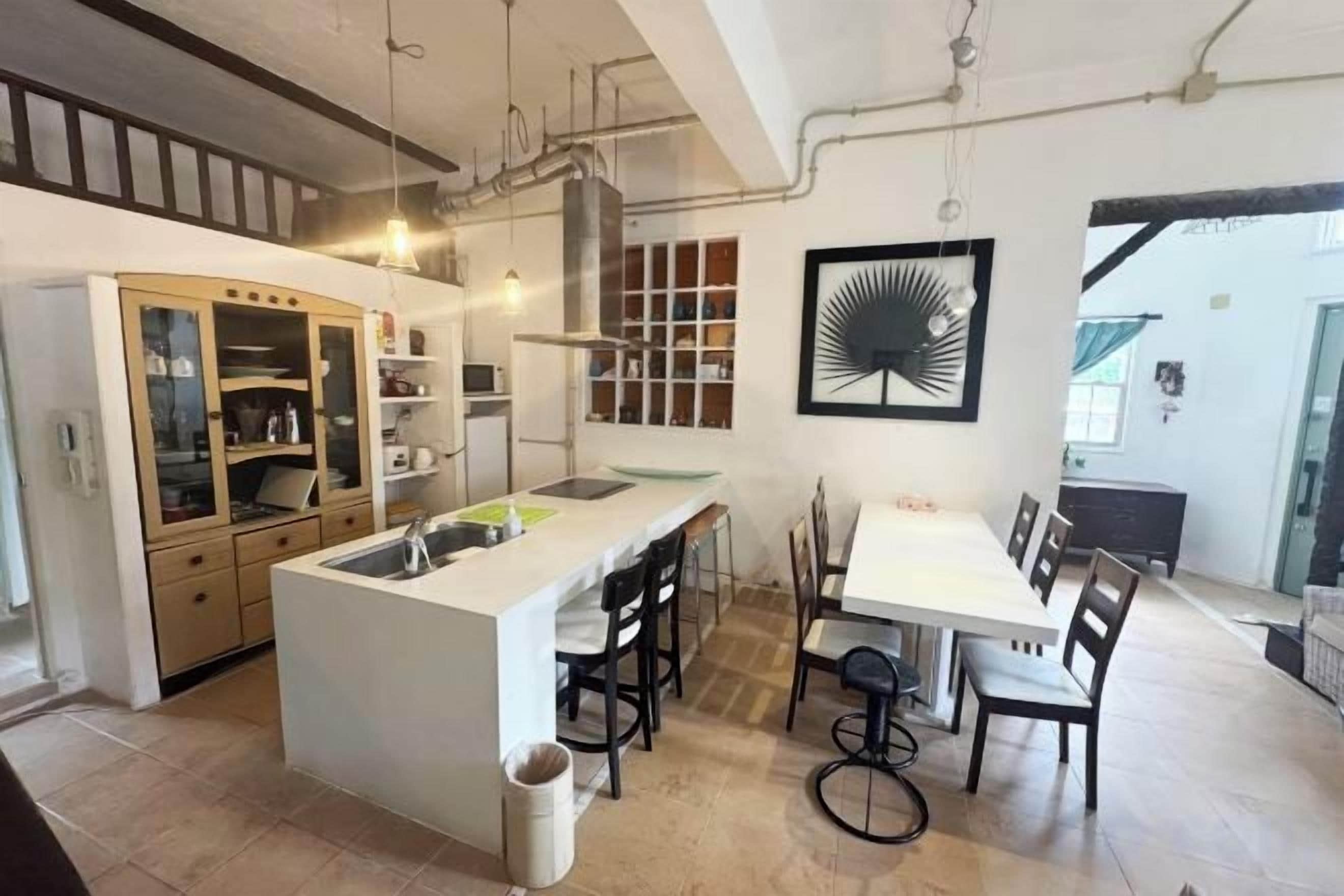 A modern kitchen with a central island, bar stools, and a dining area with a table and chairs.