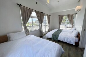 Habitación de hotel con dos camas, ventanas amplias y vistas al exterior.