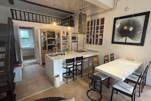 Una cocina con una isla central, taburetes de bar y una mesa de comedor con sillas.