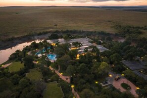 Vue aérienne d’une propriété comprenant une piscine, plusieurs bâtiments et une végétation luxuriante.