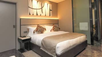 A modern bedroom with a large bed, a bedside table, and a wall-mounted abstract art piece.