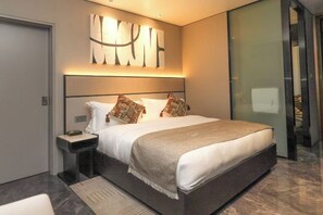 A modern bedroom with a large bed, a bedside table, and a wall-mounted abstract art piece. - Pristine Mara Bay Lodge (Koyaki)