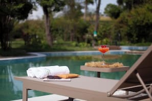Un coin détente au bord de la piscine, avec une serviette, une assiette de nourriture et une boisson.