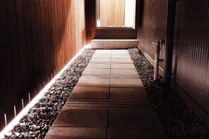 A hallway with a wooden floor, a pebble border, and a door at the end. - Ranjatai Premium (Nara)