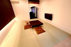 A room with a flat-screen TV mounted on the wall, a sofa, and a small rug. - Ranjatai Premium (Nara)