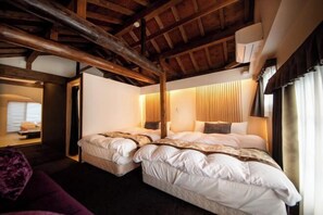 A bedroom with two beds, wooden beams, a window with curtains, and a bedside table. - Ranjatai Premium (Nara)