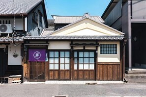 Um edifício tradicional japonês com fachada de madeira, grandes portas deslizantes e uma faixa roxa.