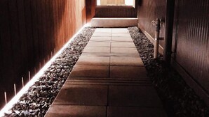 A narrow hallway with a tiled floor, wooden walls, and a door at the end. - Ranjatai Premium (Nara)