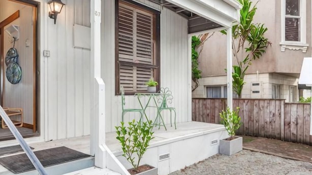 Un porche abrité avec une porte en bois, un banc et des plantes en pot.