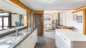 Une cuisine moderne dotée d’un îlot central, un coin repas avec une table en bois et un espace de vie comprenant un canapé et une table basse.