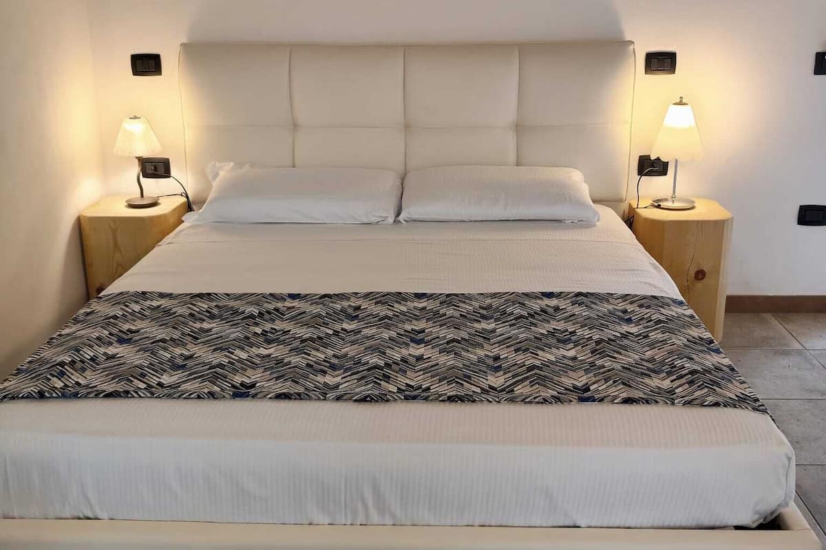 A bed with a headboard, two bedside tables, and lamps.