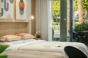 A bedroom with a bed, pillows, a bedside table, and a window with a view of the outdoors.
