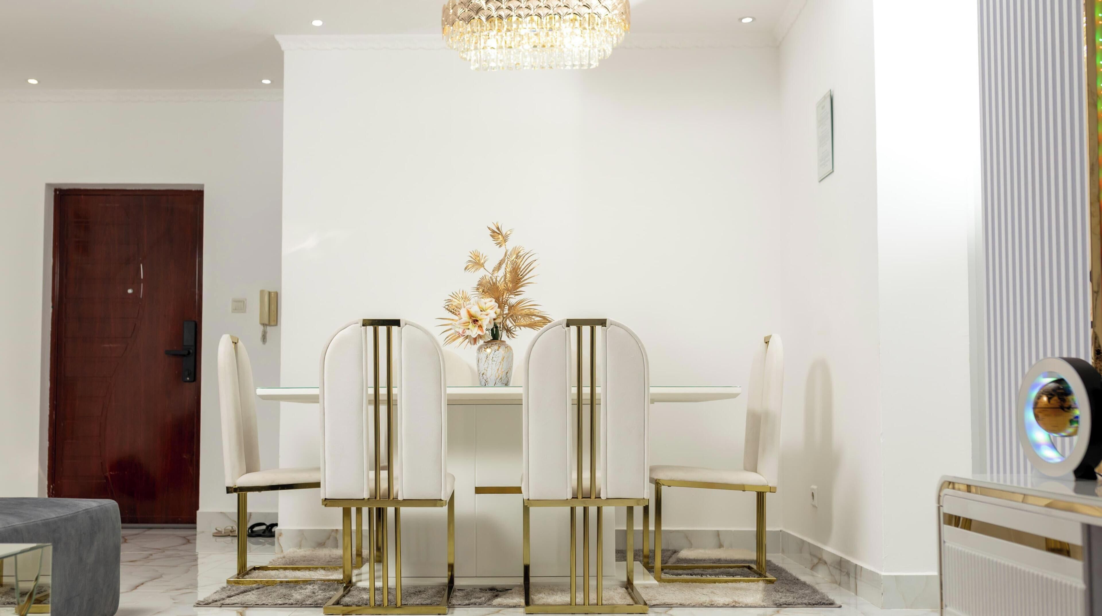 Un coin repas avec une table blanche, quatre chaises et un lustre.