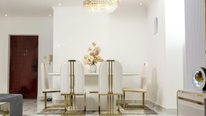 A dining area with a white table, four chairs, and a chandelier. - AM Appart's Suite Jacuzzi de luxe in Luanda (Kilamba)