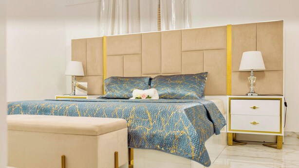 A modern bedroom with a large bed, bedside tables, and a bench. - AM Appart's Suite Jacuzzi de luxe in Luanda (Kilamba)