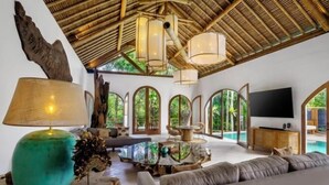 A spacious living area with a large sofa, a coffee table, and a TV. - Villa La Canopee by BaliSuperHost (Bali)