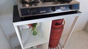 A kitchen with a gas stove and a red gas cylinder. - Chic Modern Escape (Lusaka)