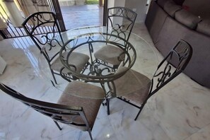 A round glass table with metal chairs in a room with a marble floor. - Chic Modern Escape (Lusaka)