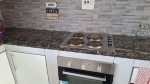 A kitchen with a granite countertop, stainless steel stove, and oven. There are three signs on the wall, one of which reads "Coffee." - Chic Modern Escape (Lusaka)