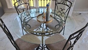A round glass table with metal chairs, a bottle, and a small decorative item on the table. - Chic Modern Escape (Lusaka)