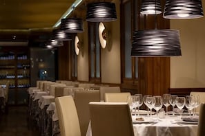 A restaurant interior with tables set for dining, hanging pendant lights, and a bar area in the background. - Heart of Madrid III Museums Theatres Sights (Madrid)