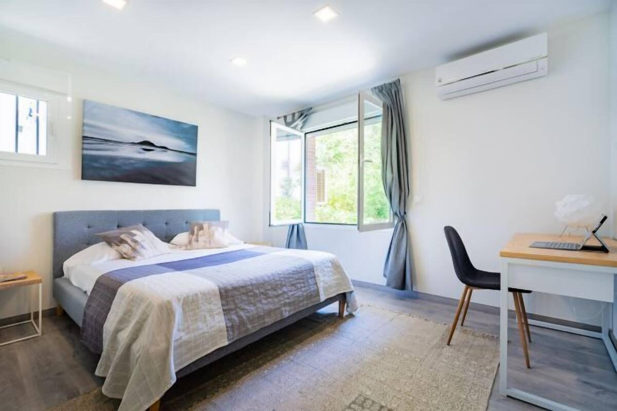 A modern bedroom with a bed, a desk, and a window.