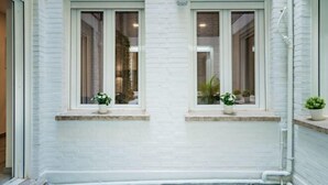 A white brick exterior with two windows, each with a small potted plant on the ledge. - Heart of Madrid III Museums Theatres Sights (Madrid)