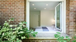A room with a bed, a window, and a brick wall. - Heart of Madrid III Museums Theatres Sights (Madrid)