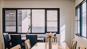 A dining area with a long table, chairs, and a vase of flowers. - DEJA HOME (Chiang Mai)