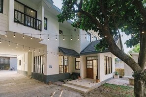 A two-story house with a covered patio, string lights, and a tree. - DEJA HOME (Chiang Mai)