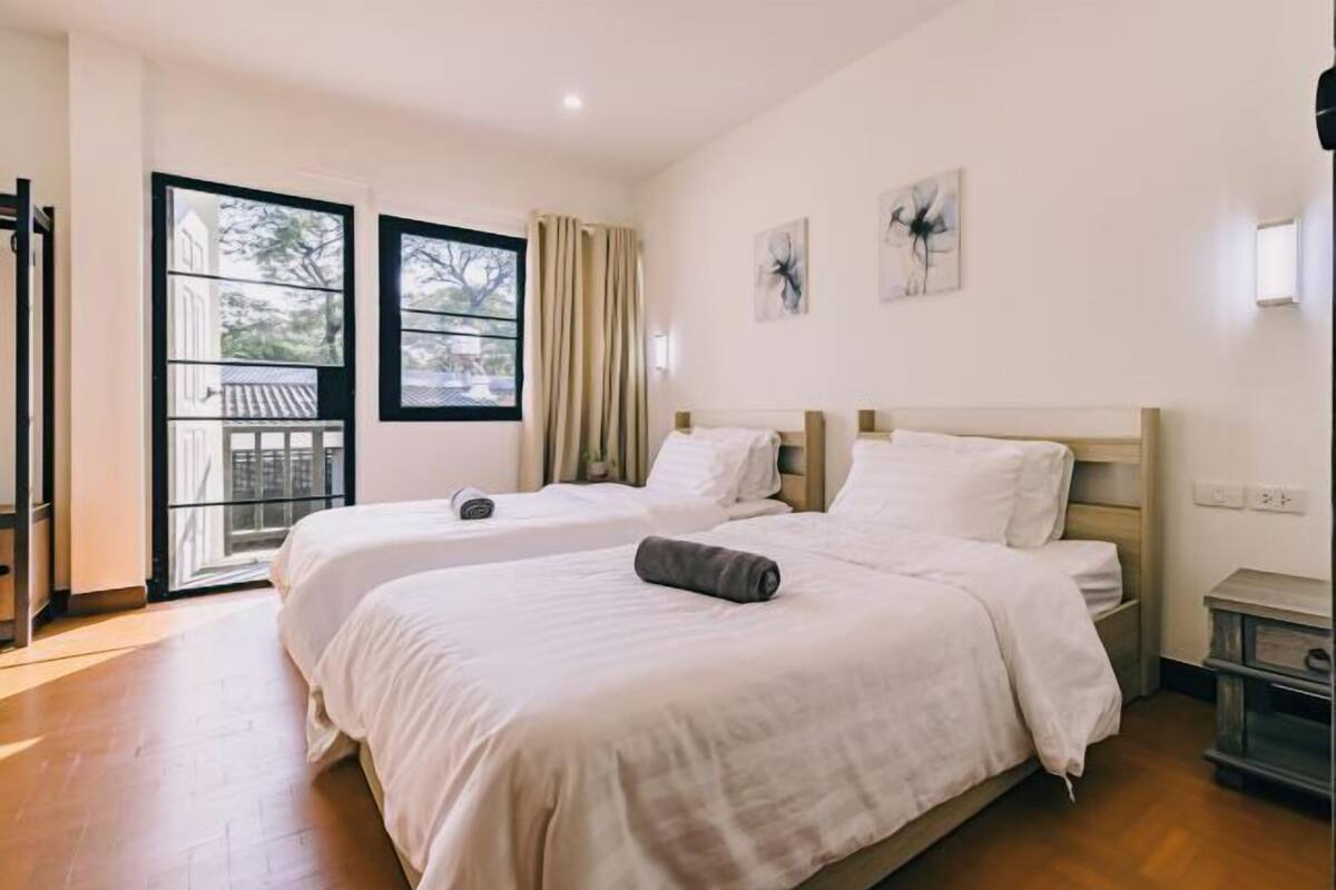A hotel room with two beds, a balcony, and a view of a building.