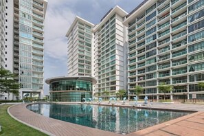 Un moderno edificio residencial con piscina, varios balcones y fachada de vidrio curvado.