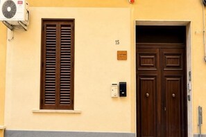 A building entrance with a double door, a window with shutters, and a number plaque. - Lucky home (Trapani)