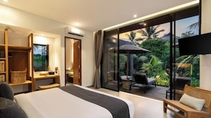 A modern hotel room with a large bed, a seating area with a view of lush greenery, and a television mounted on the wall. - Villa Palm Angels by BaliSuperHost (Bali)
