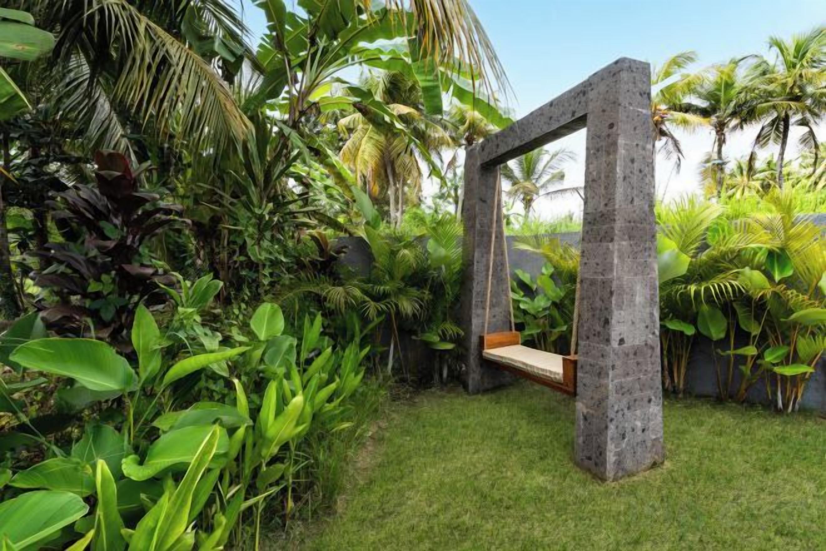 A concrete structure with a bench, surrounded by lush tropical vegetation.