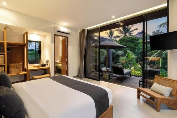 A bedroom with a large bed, a TV mounted on the wall, and a balcony with outdoor furniture. - Villa Palm Angels by BaliSuperHost (Bali)