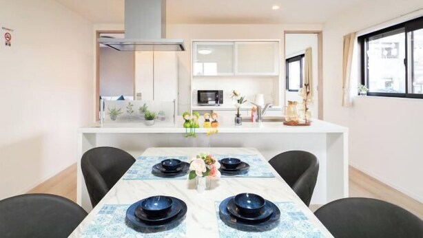 A modern kitchen with white cabinets, a microwave, and a dining area with a table set for four.
